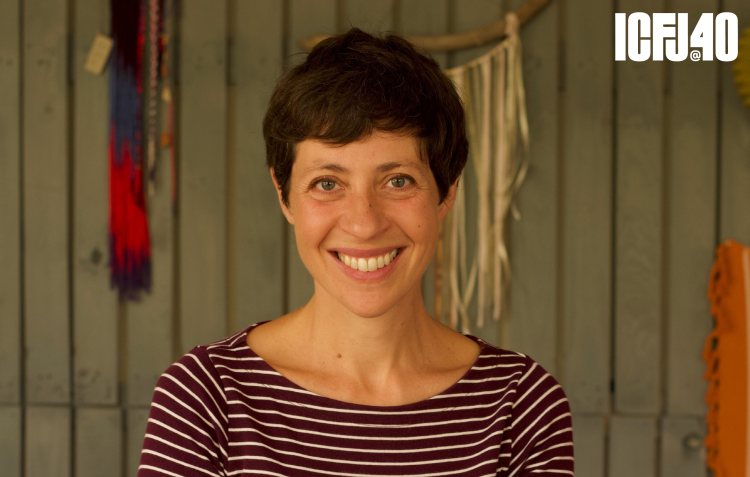 A headshot of a white brunette woman. Her hair is short and she wears a striped shirt.