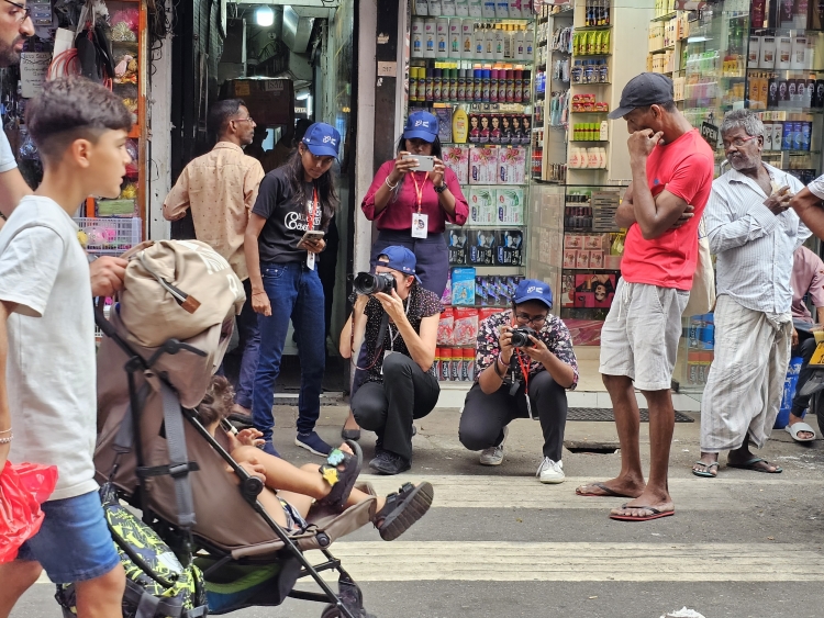 Journalists from the SLPI workshop take photos with cameras and phones on a busy Sri Lankan crosswalk.