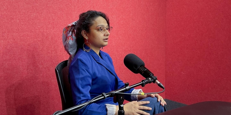 Jyoti Dwivedi sits in a recording studio, with a microphone in front of her. 