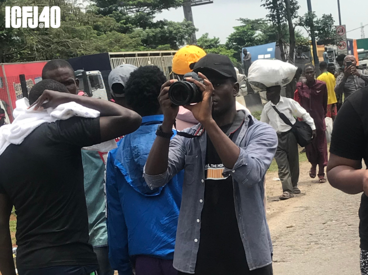 A photograph of Olakunle Mohammed holding a camera in a crowd on people. 