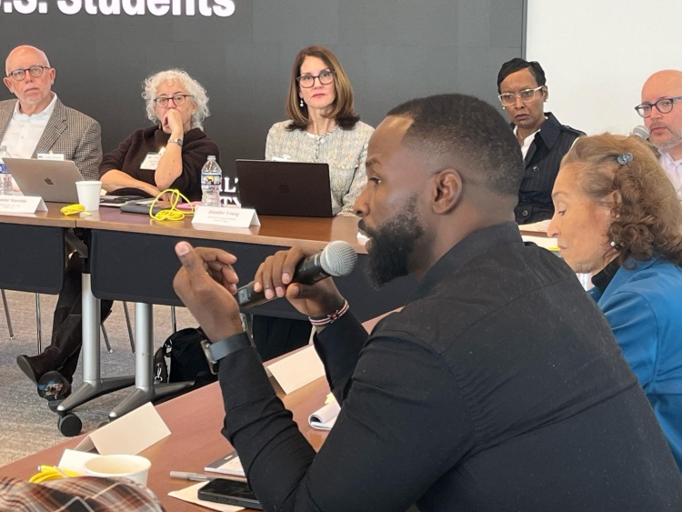 A participant speaks into a microphone at a roundtable event